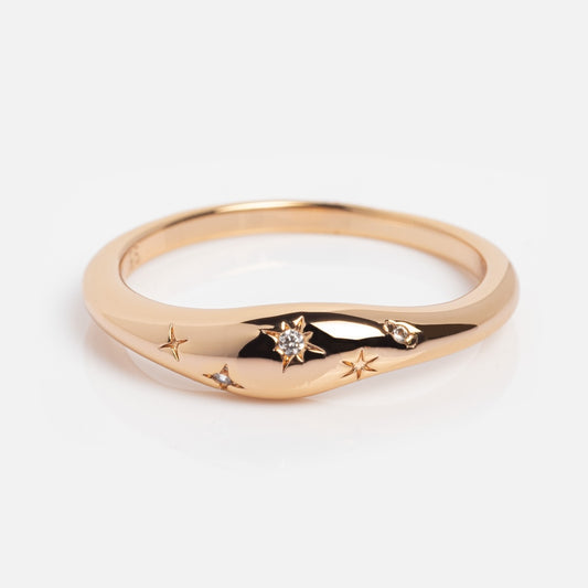 The Cosmic Dome Ring is a unique gold-plated ring with engraved star patterns, featuring a central star set with a small diamond and additional smaller stars, displayed on a white background.
