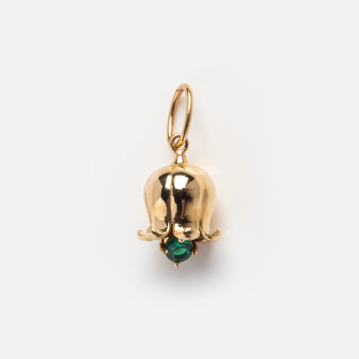 The Solid Gold Birth Flower Bud Charm, shaped like a bellflower and accented with a small green gemstone at the base, is displayed against a plain white background.