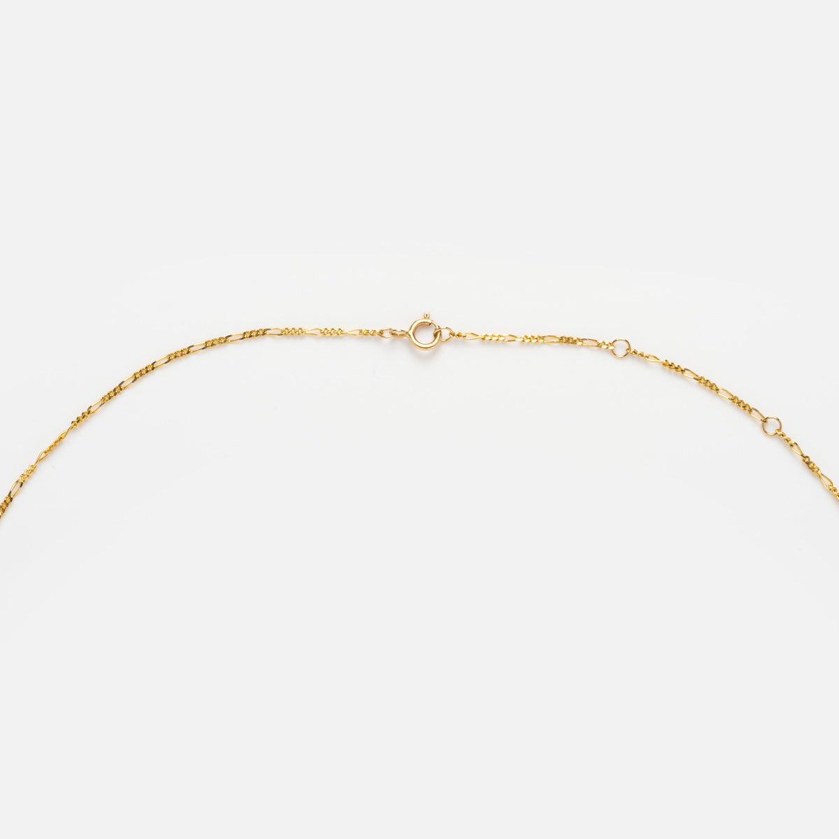 The Solid Gold Figaro Chain, made from 9k solid gold and featuring a small circular clasp, is displayed in a gentle curve on a plain white background.