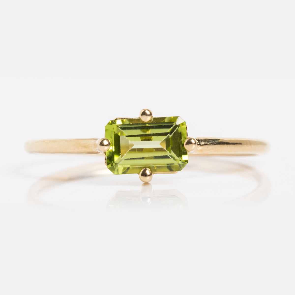 The 14k Mod Love Birthstone Ring features an emerald-cut green gemstone set with four prongs on a slim gold band, shown against a white background.