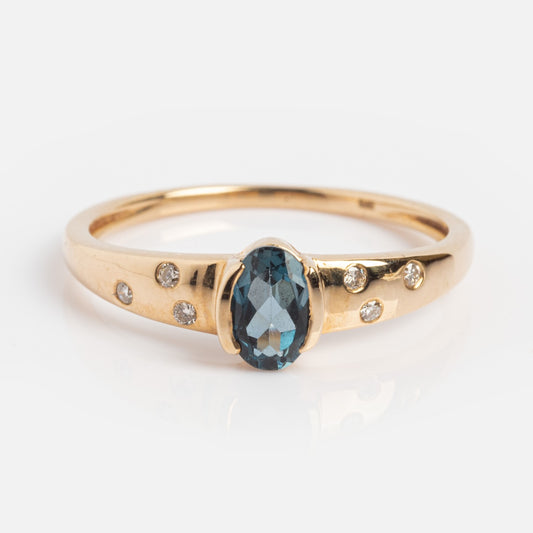 The Solid Gold London Blue Topaz Modern Signet Ring features an oval blue gemstone at the center with three round diamonds on each side, displayed against a white background.