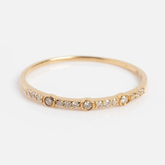 A delicate solid gold stacking band featuring small round white sapphires along the band, with three slightly larger sapphires spaced evenly—this Solid Gold Delicate White Sapphire Stacking Band is shown on a white background.