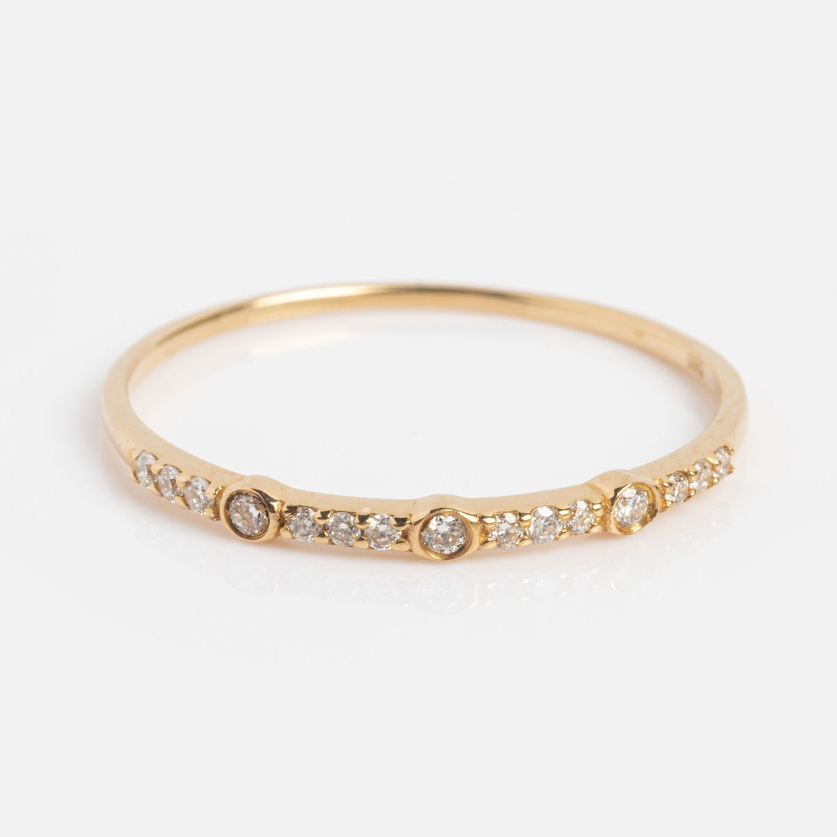 The Solid Gold Tiny Fuck Sapphire Stacking Ring Set features thin gold bands, each adorned with small sapphires and three larger stones spaced evenly among them.