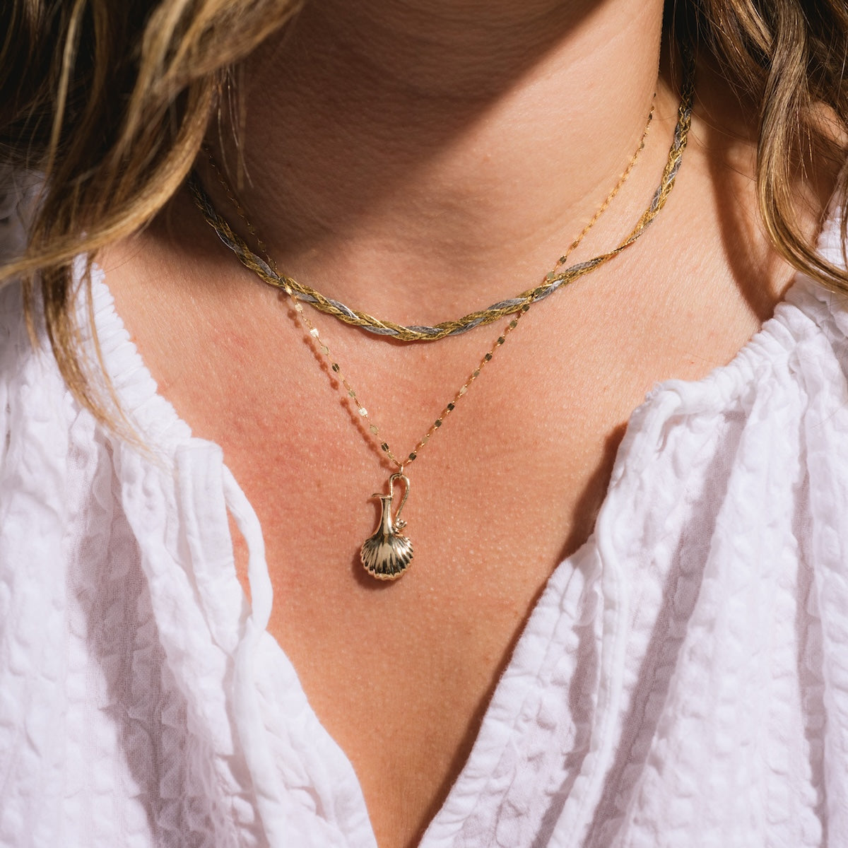 Close up of Aphrodite Vessel Charm on a necklace worn on figure