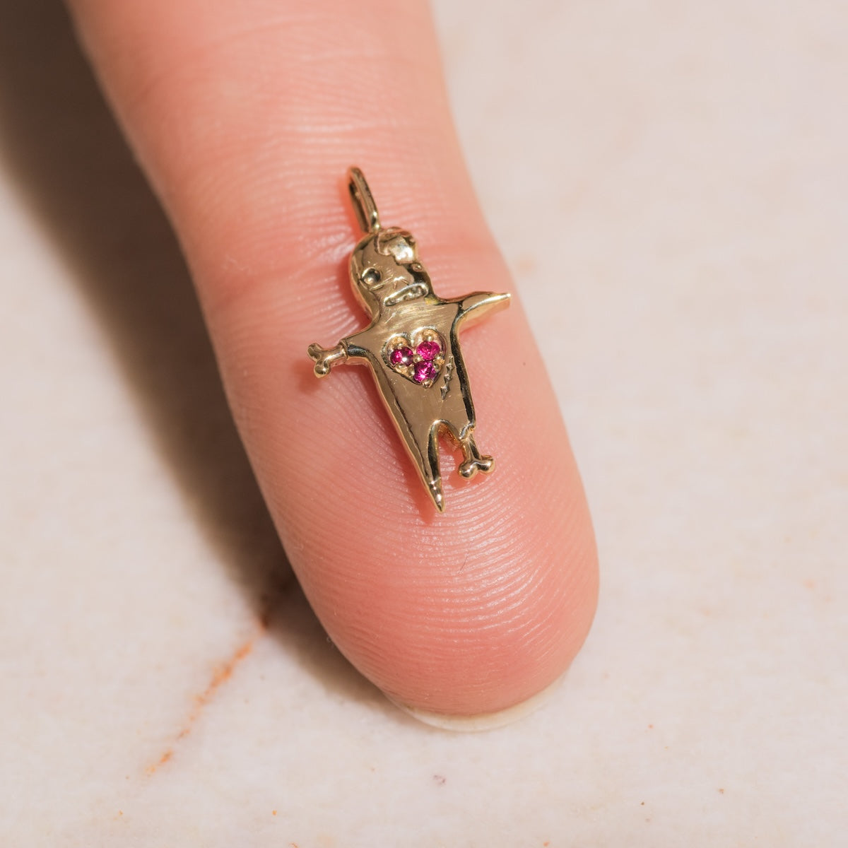 Sofia Zakia Ghoul with a Heart of Gold Charm laid on finger for scale