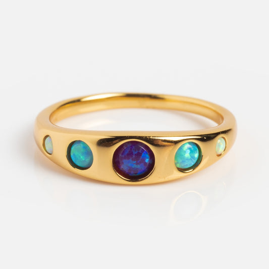The Blue Opal Ombre Via Ring features a central round purple-blue opal between two smaller greenish-blue opals, creating a stunning ombre effect on a polished gold vermeil band against a white background.