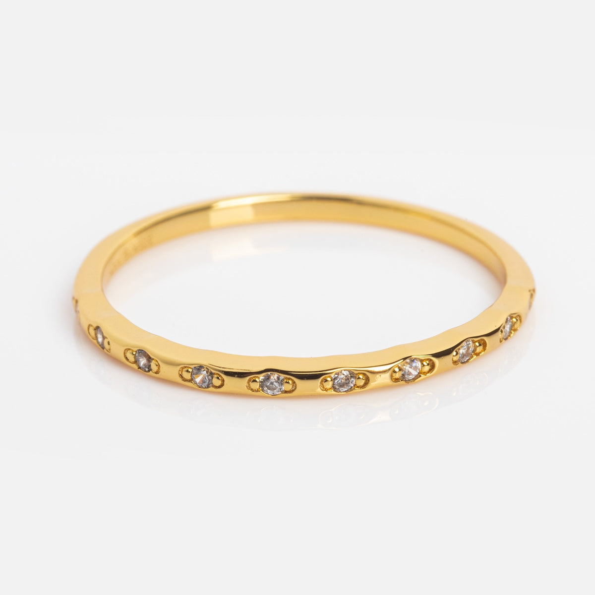 The Regency Stacking Ring is a slim yellow gold plated band with small, evenly spaced clear gemstones encircling the band, shown on a white background.
