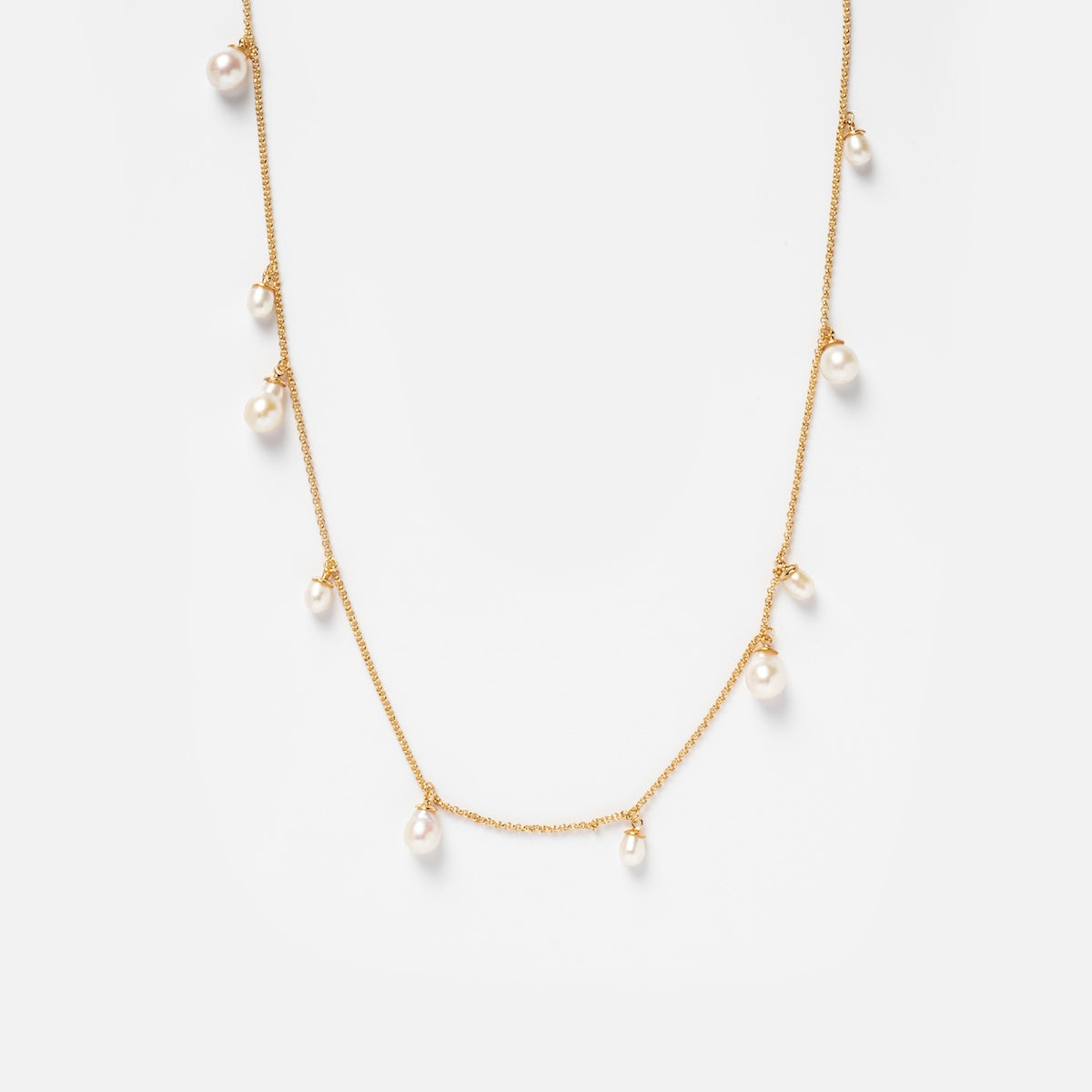 The Amelie Necklace Sample is a delicate 14k yellow gold plated chain with nine evenly spaced dangling Freshwater pearls, shown against a plain white background.