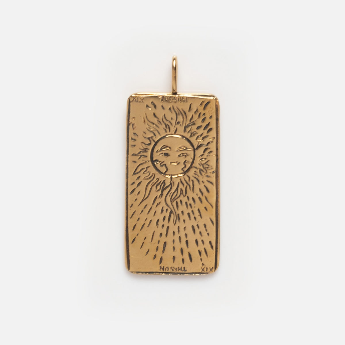 Tarot Card Charm: A gold rectangular pendant engraved with a sun face and radiating lines, accented by small details. This spiritual jewelry piece has a top loop for attaching to a chain.