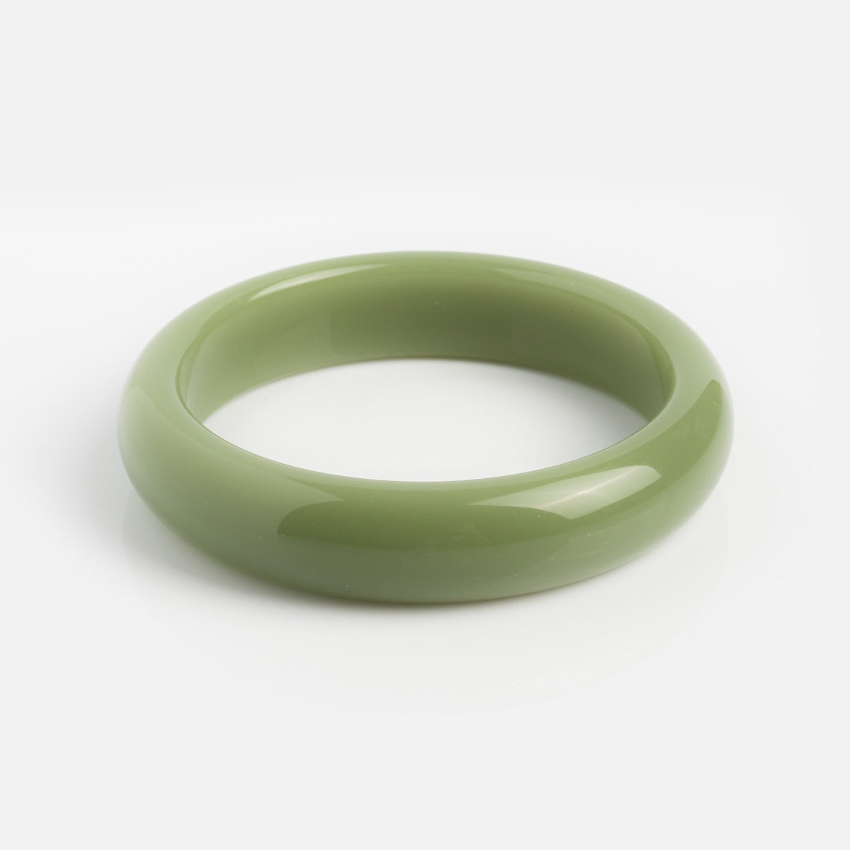 A smooth, glossy Smoke Green Jade Quartzite Stone Bangle with a rounded shape is displayed on a white background.