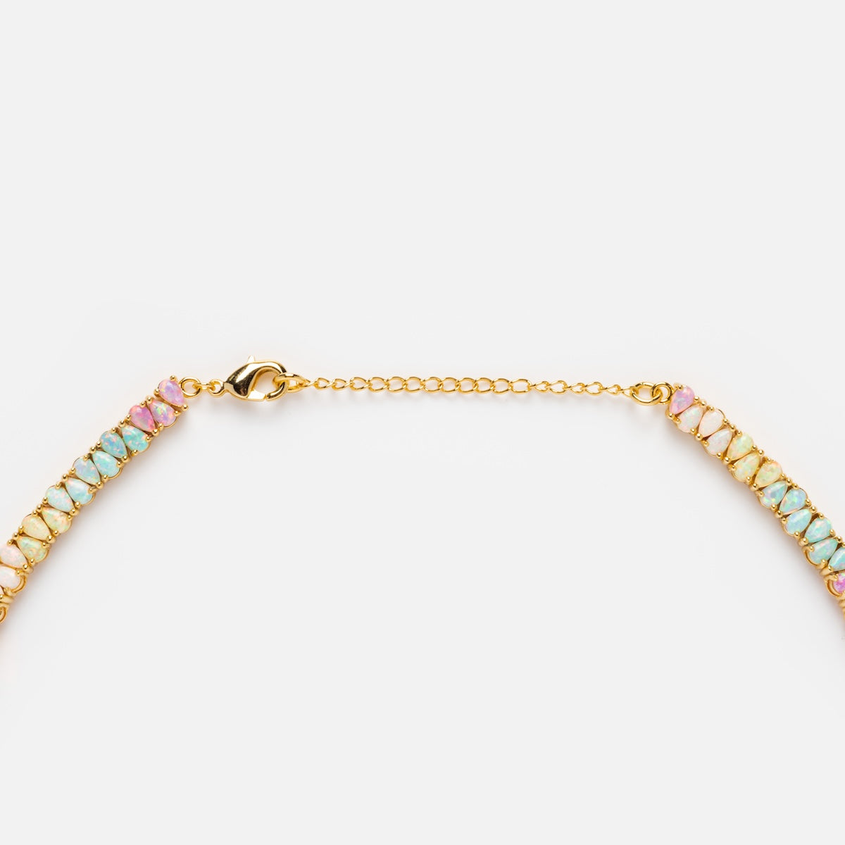 A close-up of the Opal Dancing Dreams Tennis Necklace shows a gold chain with pastel pink, blue, and green simulated opal-like beads, lobster clasp, and adjustable extension chain against a white background.