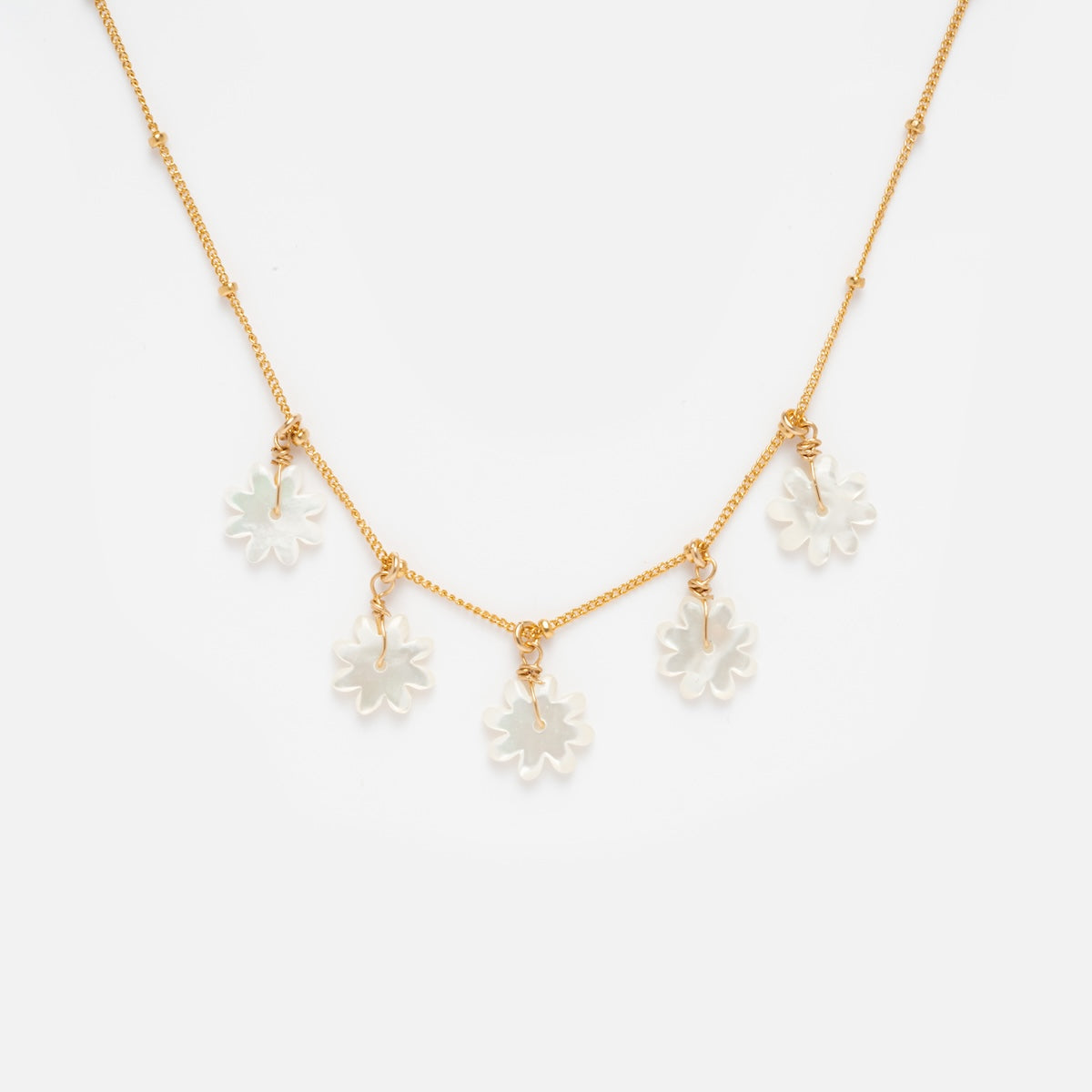 Mother of Pearl Flower Shaker Necklace Sample: Features a gold filled chain with five handmade white mother of pearl flower charms, evenly spaced along the chain and shown on a plain white background.