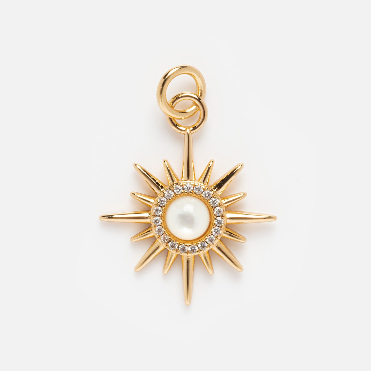 Charms by Elizabeth Stone: A gold sunburst pendant featuring a central mother of pearl, accented by clear gemstones and celestial charms, shown on a plain white background.
