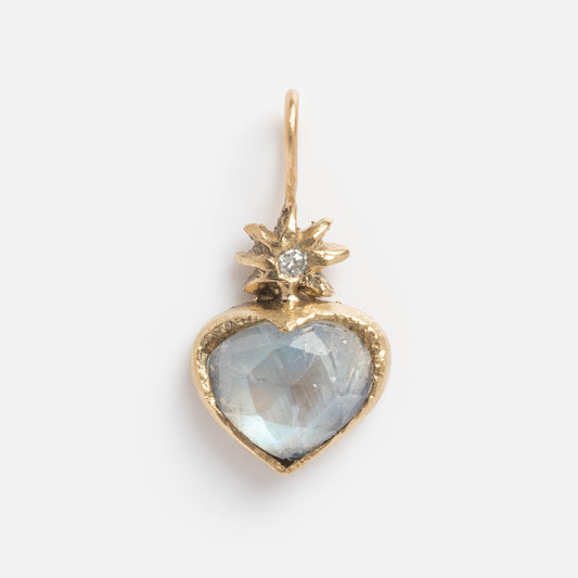 The Guided Heart Pendant Charm features 14k solid yellow gold with a faceted translucent blue gemstone and a diamond starburst detail, set against a plain white background.