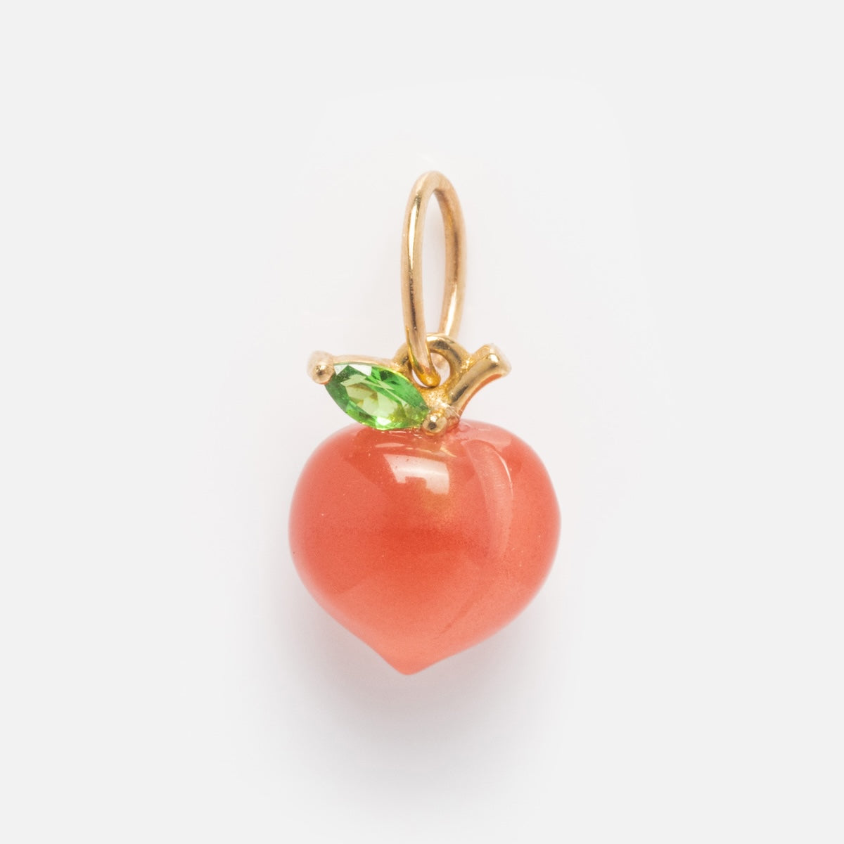 The Solid Gold Foodie Charm is a 9k yellow gold peach-shaped pendant, showcasing a smooth orange-pink fruit with a green leaf and gold stem—an elegant necklace displayed on a plain white background.