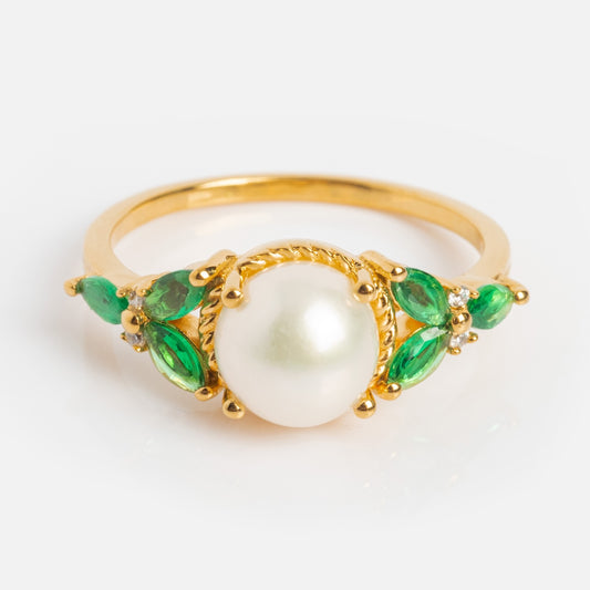 The Vintage Inspired Green CZ and Pearl Statement Ring showcases a large central white pearl, accented by marquise-cut green CZ stones and small round diamonds on each side, displayed against a white background.