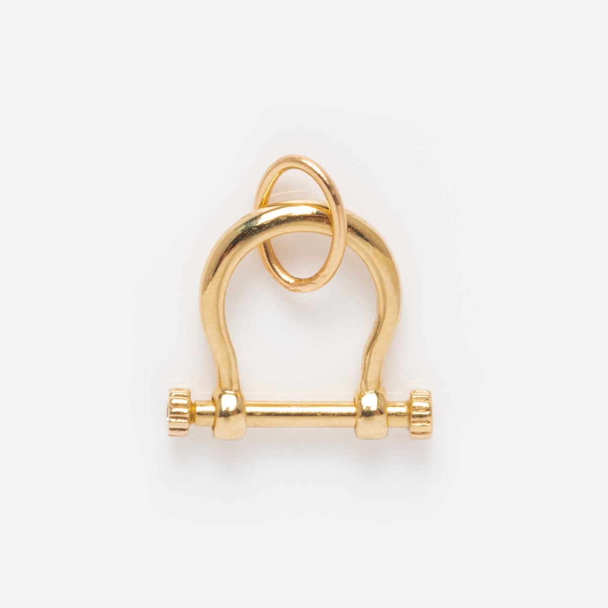 The Solid Gold Charm Clip features a curved top, horizontal bar with screw-like ends, and a small gold ring—ideal for attaching to bracelets or crafting a personalized necklace.