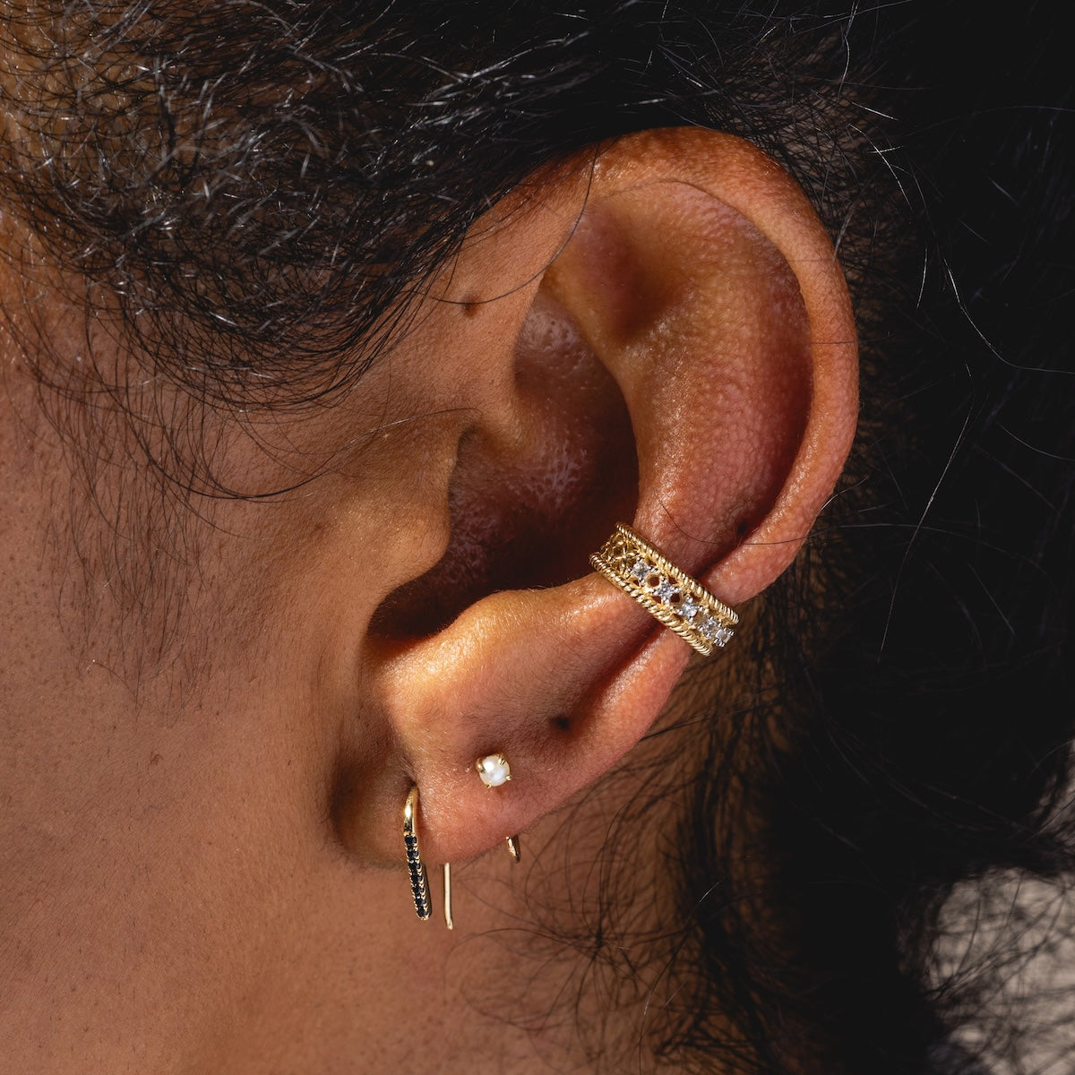 Close-up of a persons ear wearing Solid Gold Pearl Ear Huggers—elegant solid gold hoops accented with pearls, perfect for everyday style.