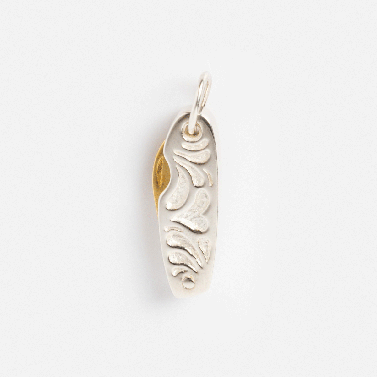 Charms by Hunt of Hounds: A sterling silver pendant with an abstract, textured design, accented by a touch of gold vermeil along the left edge and finished with a small loop on top for added charm.