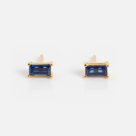 The Birthstone Baguette Studs are yellow gold vermeil earrings featuring rectangular blue gemstones, shown on a white background.