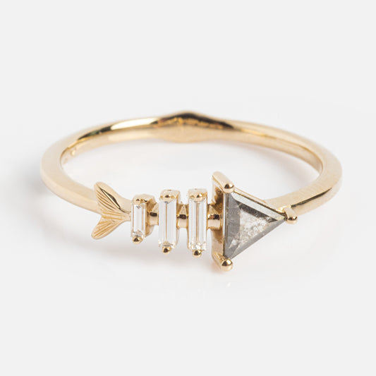 The Gold Fish Bone Ring with Triangle and Baguette Cut Diamond features a fishbone design with a triangle diamond head, three baguette cut diamonds as the body, and a gold tail on a sleek gold band for an elegant look.