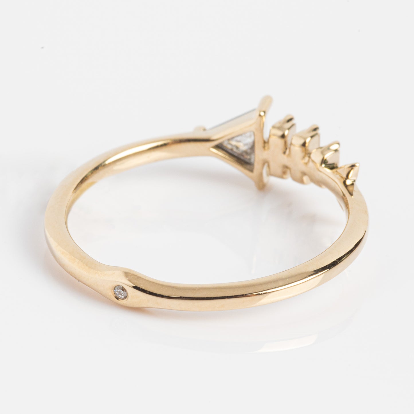 The Gold Fish Bone Ring with Triangle and Baguette Cut Diamond features a geometric fishbone design accented by unique diamond cuts, displayed on a white background—an elegant choice for modern style enthusiasts.