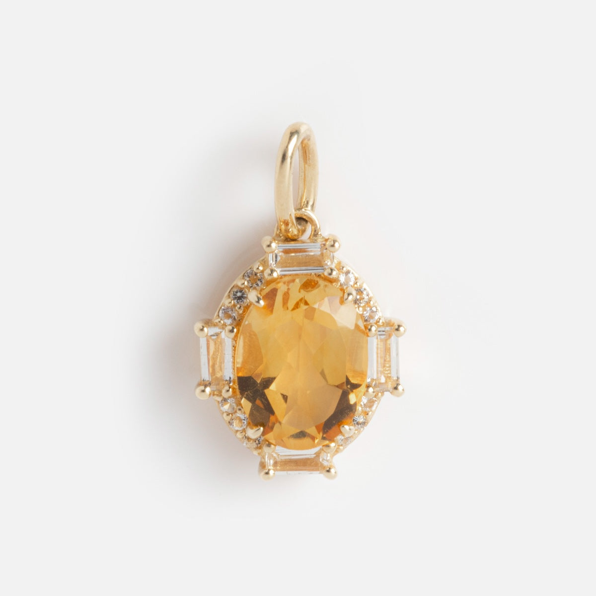 The Solid Gold Vintage Inspired Birthstone Charm features an oval yellow gemstone surrounded by clear stones and baguette-cut accents, set in delicate gold with a small loop for attaching to your favorite chain.