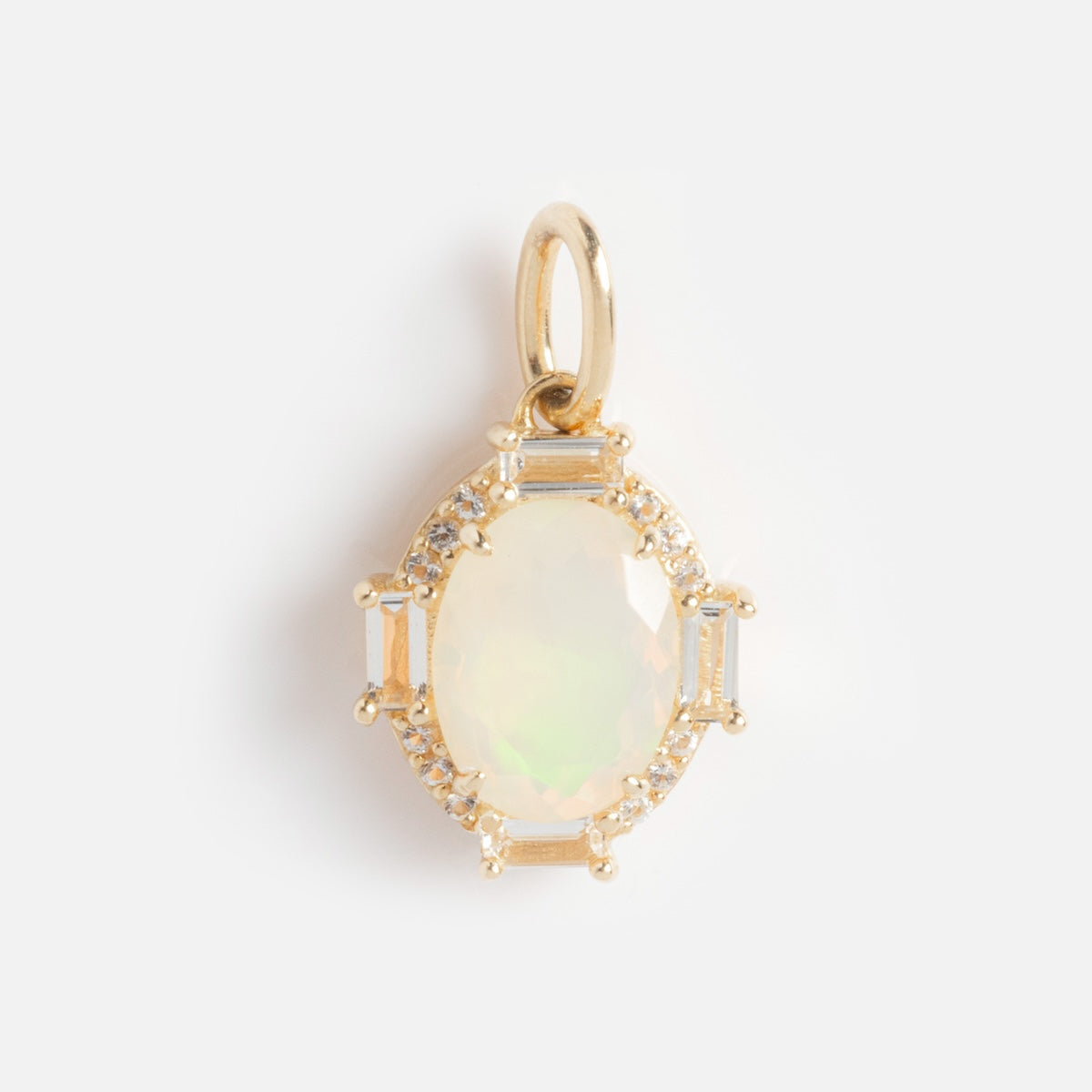 The Solid Gold Vintage Inspired Birthstone Charm features an oval opal gemstone, framed by small diamonds and rectangular baguette stones in a delicate gold setting with a loop for necklace attachment.