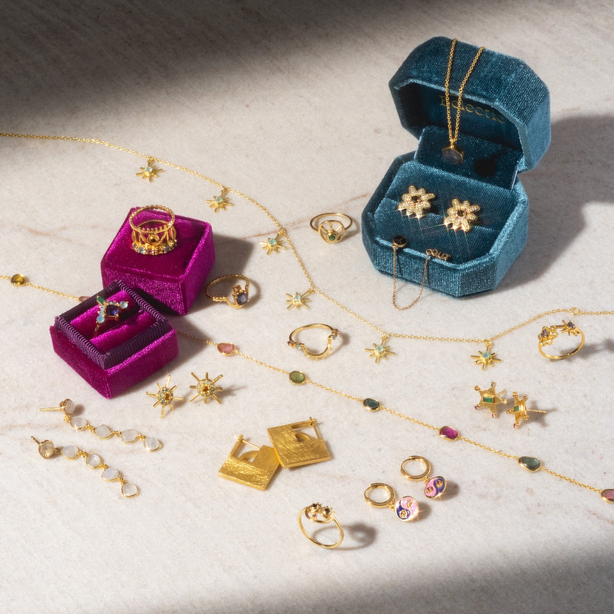 Sol Stud Earrings in gold with vibrant citrine stones, displayed on marble alongside teal and purple velvet jewelry boxes.