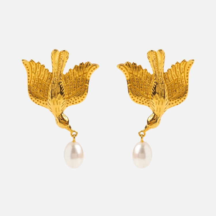 The Sparrow Earrings are gold vermeil bird-shaped earrings with detailed wings, each holding a single white pearl drop in their beaks, shown against a plain white background.