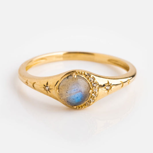 A celestial accessory: the Solid Gold Lunar Labradorite Signet Ring showcases a round labradorite center, crescent diamond accents, and star engravings along both sides of its solid gold band.