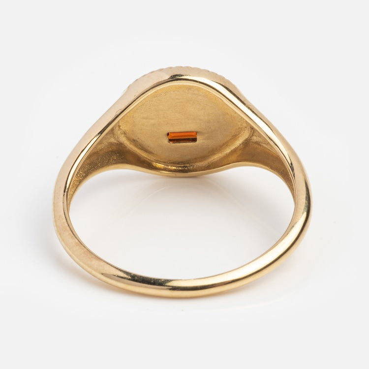 The Solid Gold Quhier Que Demain Signet Ring is shown from below, highlighting its flat inner surface with a small rectangular orange detail in the center, set against a plain white background.