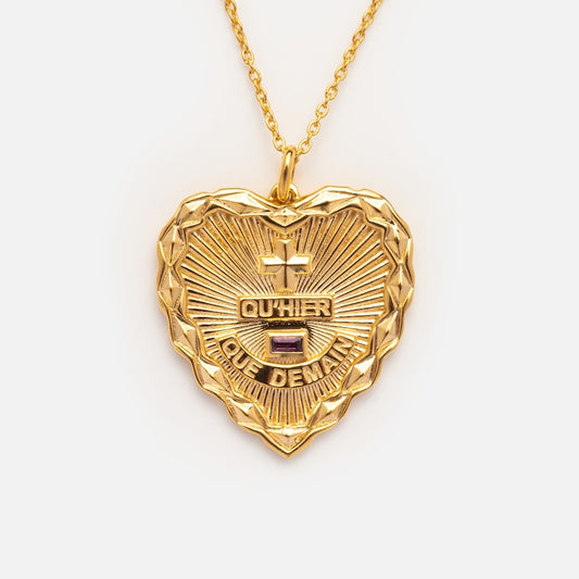 The Quhier Que Demain Heart Pendant Necklace features a gold heart with a textured border, sunburst pattern, two engraved crosses, and the words QUHIER and QUE DEMAIN on a gold chain—a classic French love piece.
