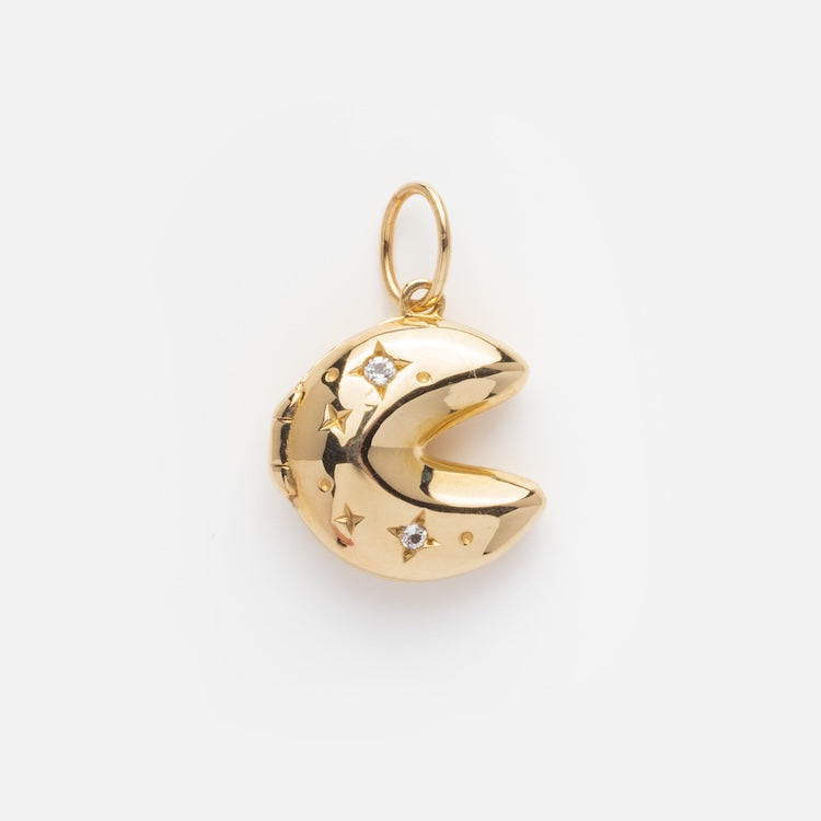 The Solid Gold Locket Charm is a crescent moon pendant adorned with small stars and sparkling stones, featuring a loop for attaching to a necklace or bracelet, displayed on a plain white background.