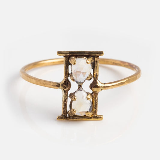 The Amulet Hourglass Ring is crafted in 14k solid yellow gold with an open rectangular frame and two vertically set clear gemstones for an hourglass effect. This moonstone ring brings mystique and elegance to any look.