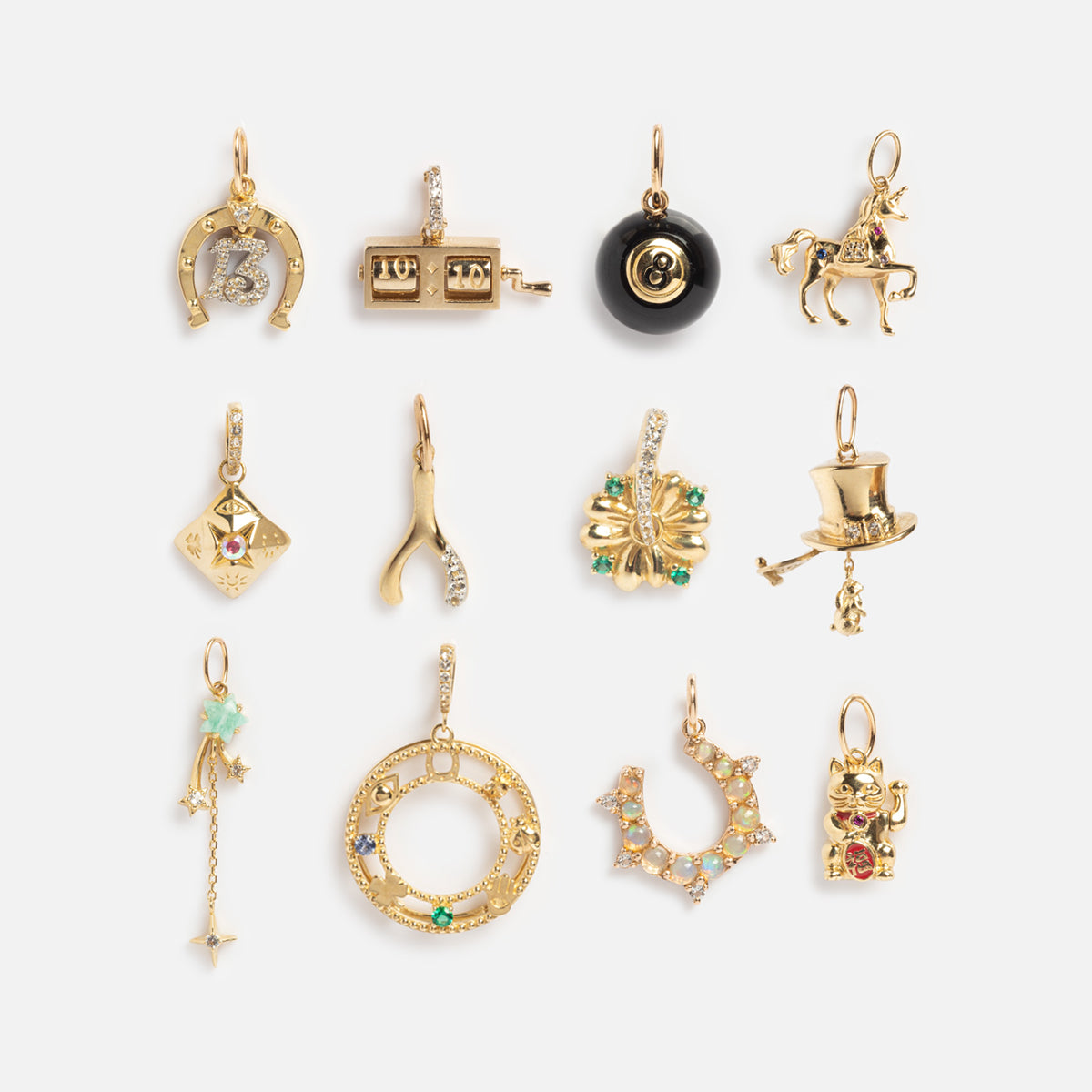 Twelve Solid Gold Lucky Charms, featuring designs like a horseshoe, slot machine, 8-ball, horse, dice, and more, are arranged in rows on a white background.