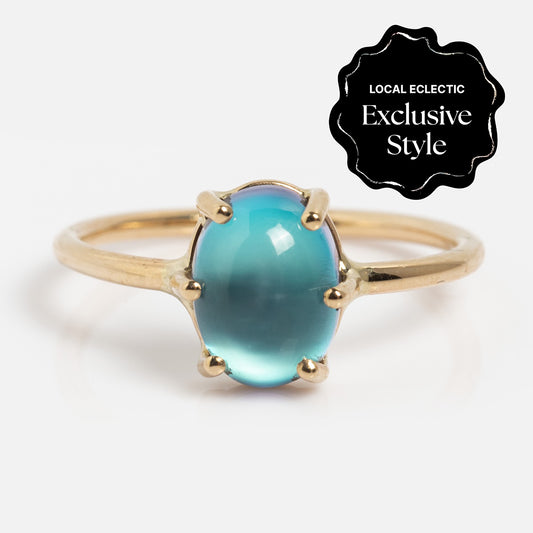The 14k Blue Crush Cats Eye Moonstone Solitaire Ring features a striking blue cats eye moonstone set in 14k gold.