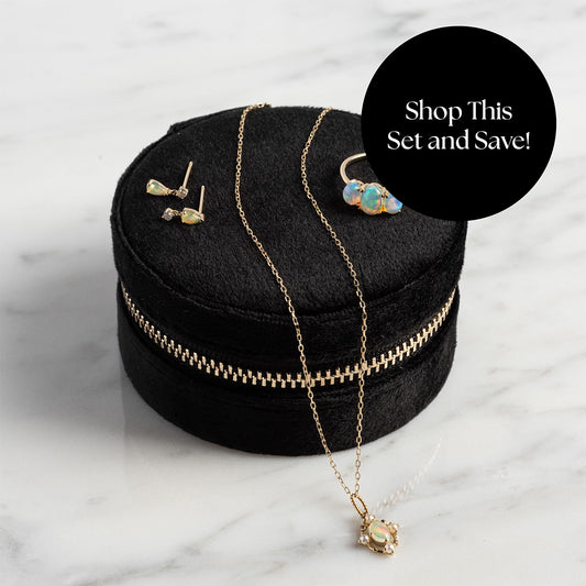 The Solid Gold 2025 October Capsule Opal Statement Set with Free Gift—featuring earrings, ring, and necklace—shown in a zippered round black velvet case on marble. A black circle overlay reads: Shop This Set and Save!.