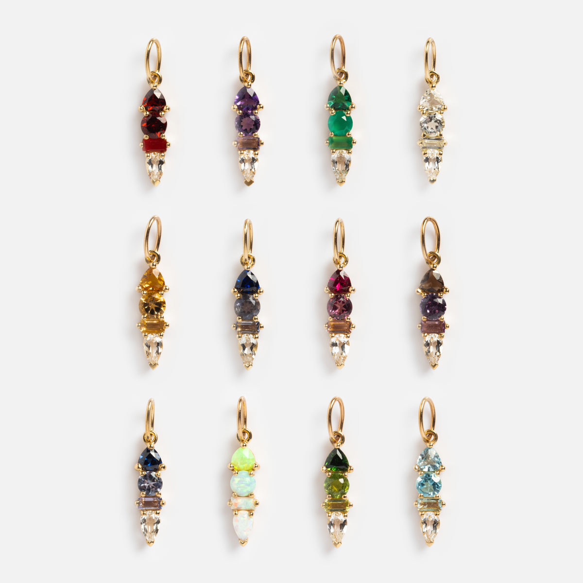Twelve Solid Gold Modern Ombre Birthstone Charms—each with three vertically stacked, multicolored gemstones—are displayed in three rows of four on a white background. Each solid gold charm has a unique ombre color combination.