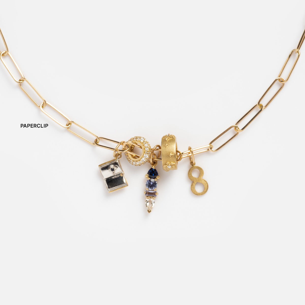 The Solid Gold Chain for Charms is shown on a white background, featuring five assorted jeweled charms: a ring, rectangle with stones, bejeweled drop, the number eight, and more.