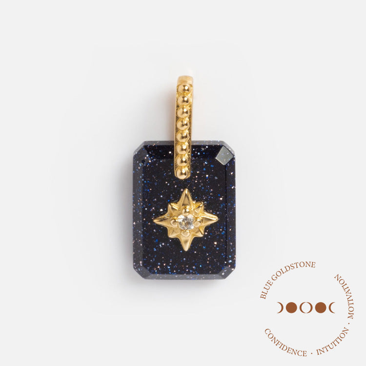 The Solid Gold Crystal Amulet Charm for Manifestation is a rectangular blue goldstone pendant with a gold star and center gemstone, hanging from a gold chain bail. It highlights Blue Goldstone’s confidence and intuition-boosting properties.