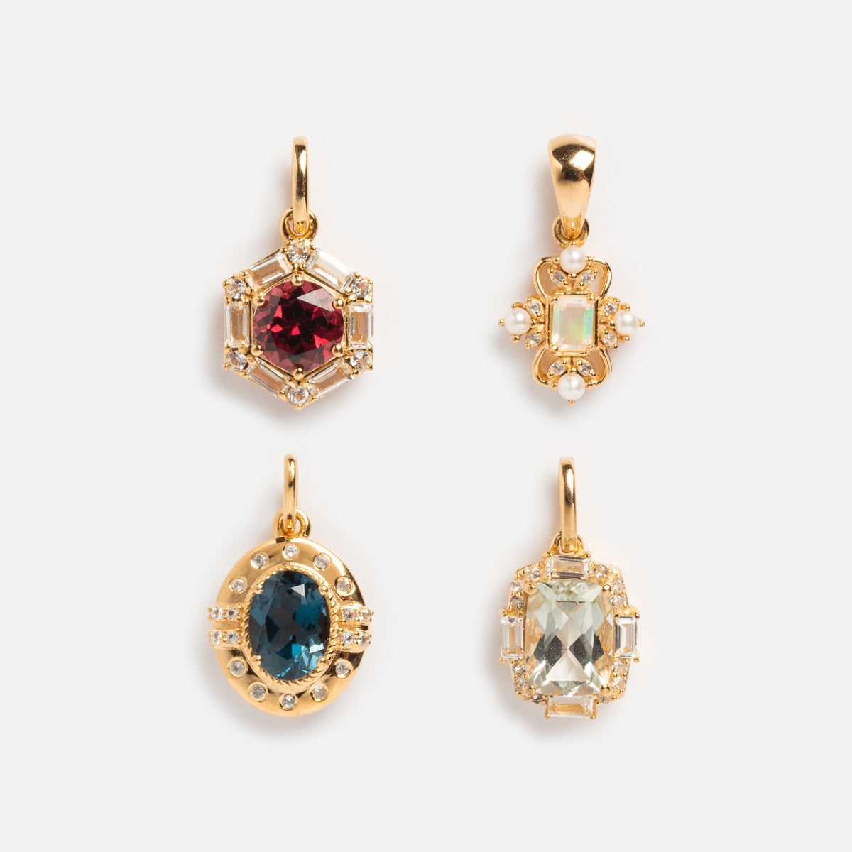 The Vintage Inspired Pendant Charm collection includes four ornate gold vermeil pendants with colored gemstones: a red hexagon, white floral, blue oval, and light green rectangle—each accented with clear stones.