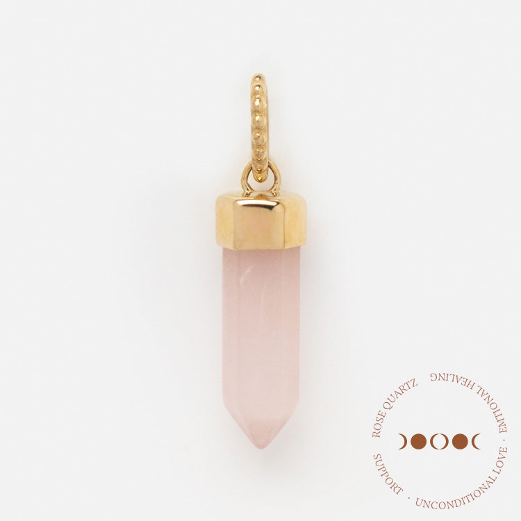 The Solid Gold Crystal Charm for Manifestation features a gold-capped rose quartz pendant with a beaded gold loop, shown on a white background. A circular emblem with text and a triple moon symbol appears in the lower right corner.