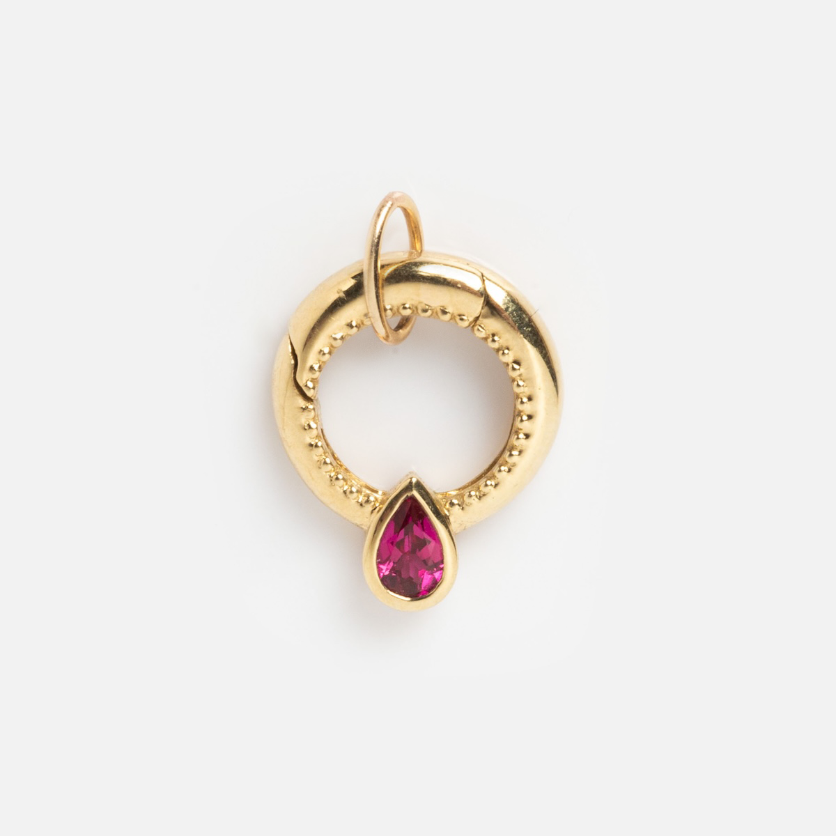 The Solid Gold Charm Clip features a circular design with beaded details and a teardrop pink gemstone, made for easy charm attachment—ideal for creating your own personalized necklace.