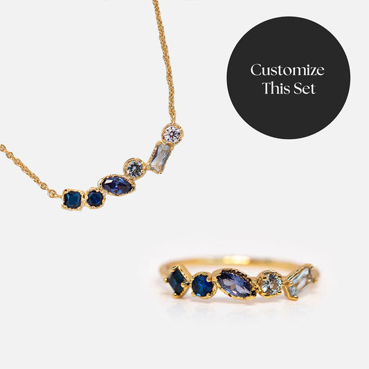 The Shades of You Ombre Birthstone Ring and Necklace Gift Set features unique blue and clear gemstones. A black circular label reads Customize This Set. Displayed on a white background, it makes a personalized gift.