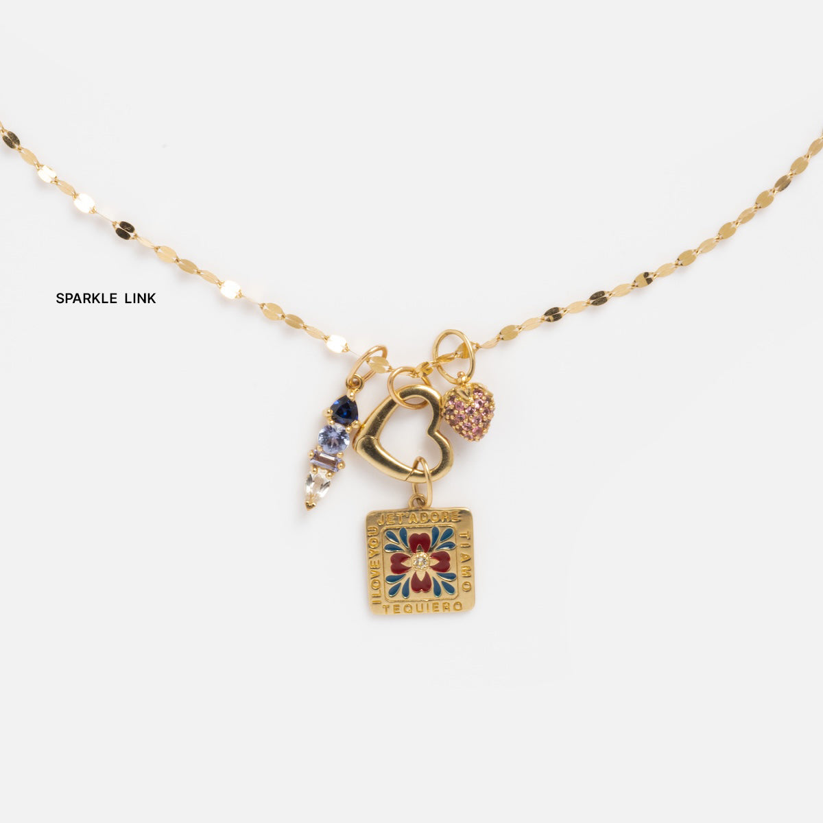 Solid Gold Chain for Charms featuring a square floral Te quiero charm, gold heart, three clustered beads, and a pink heart—each element shining delicately against a white background.