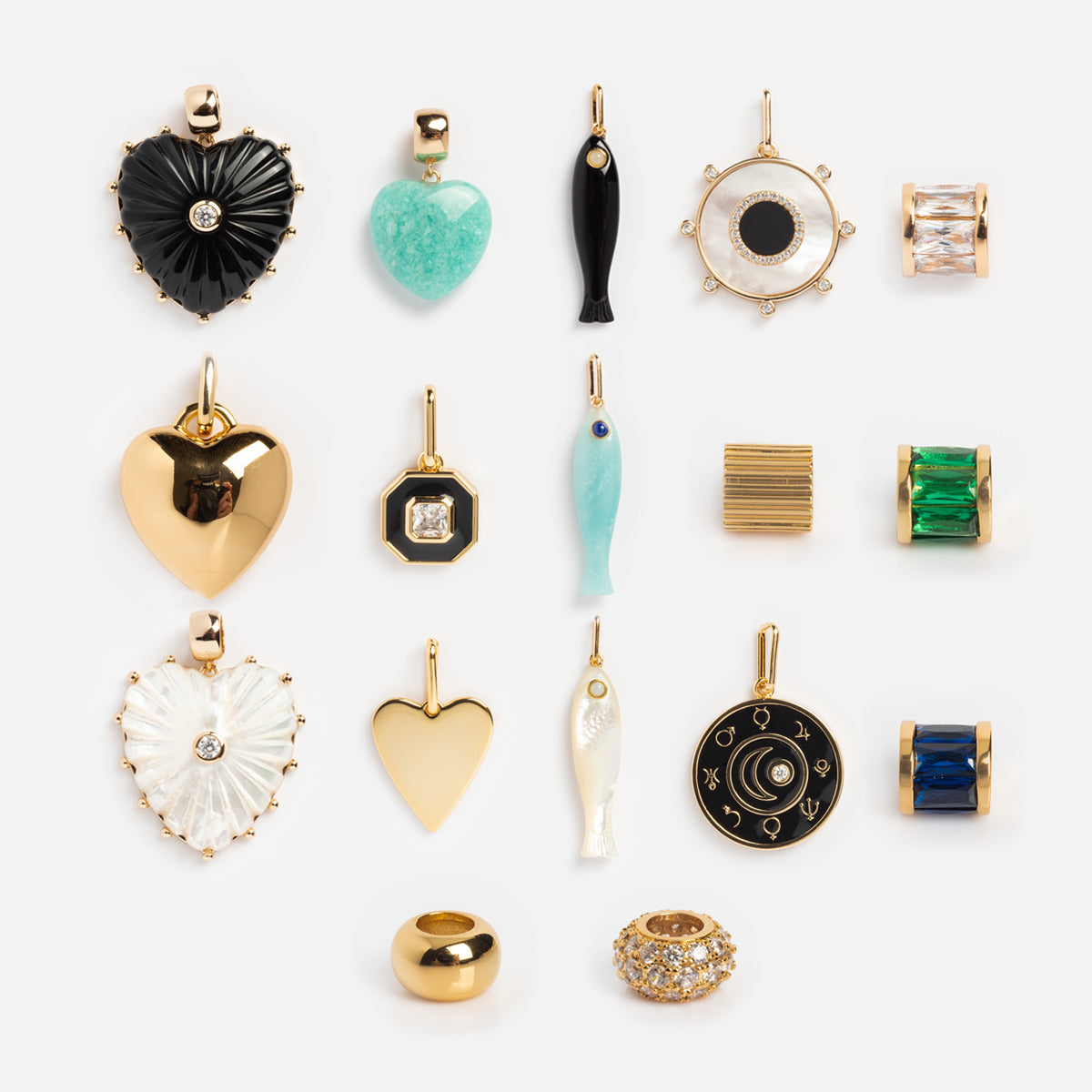 Charms by Thatch: sixteen assorted gold-plated charms—including hearts, fish, geometric shapes, a mother of pearl charm, and a crescent moon—arranged in four neat rows on a light background.