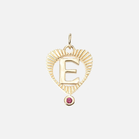 The Sunbeam Letter Heart Charm is a 10k gold heart-shaped pendant with a ribbed texture, the letter E at the center, and a pink birthstone at the bottom—perfect for creating a stunning personalized necklace.