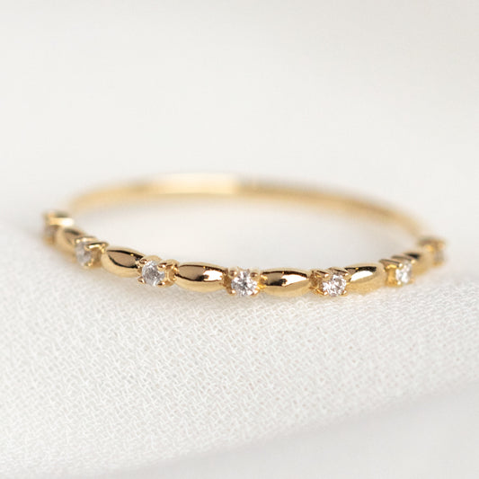 The 14k Delicate Diamond Celebration Band is crafted in solid yellow gold, with small round lab-created diamonds evenly spaced along the band and displayed on a soft white textured surface.