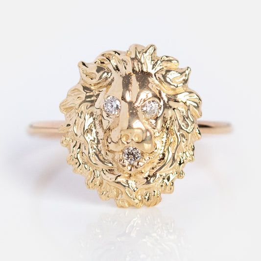 The Courage the Lion Ring is an antique-style 14k yellow gold piece with three sparkling gemstones set in its eyes and mouth, shown on a plain white background.